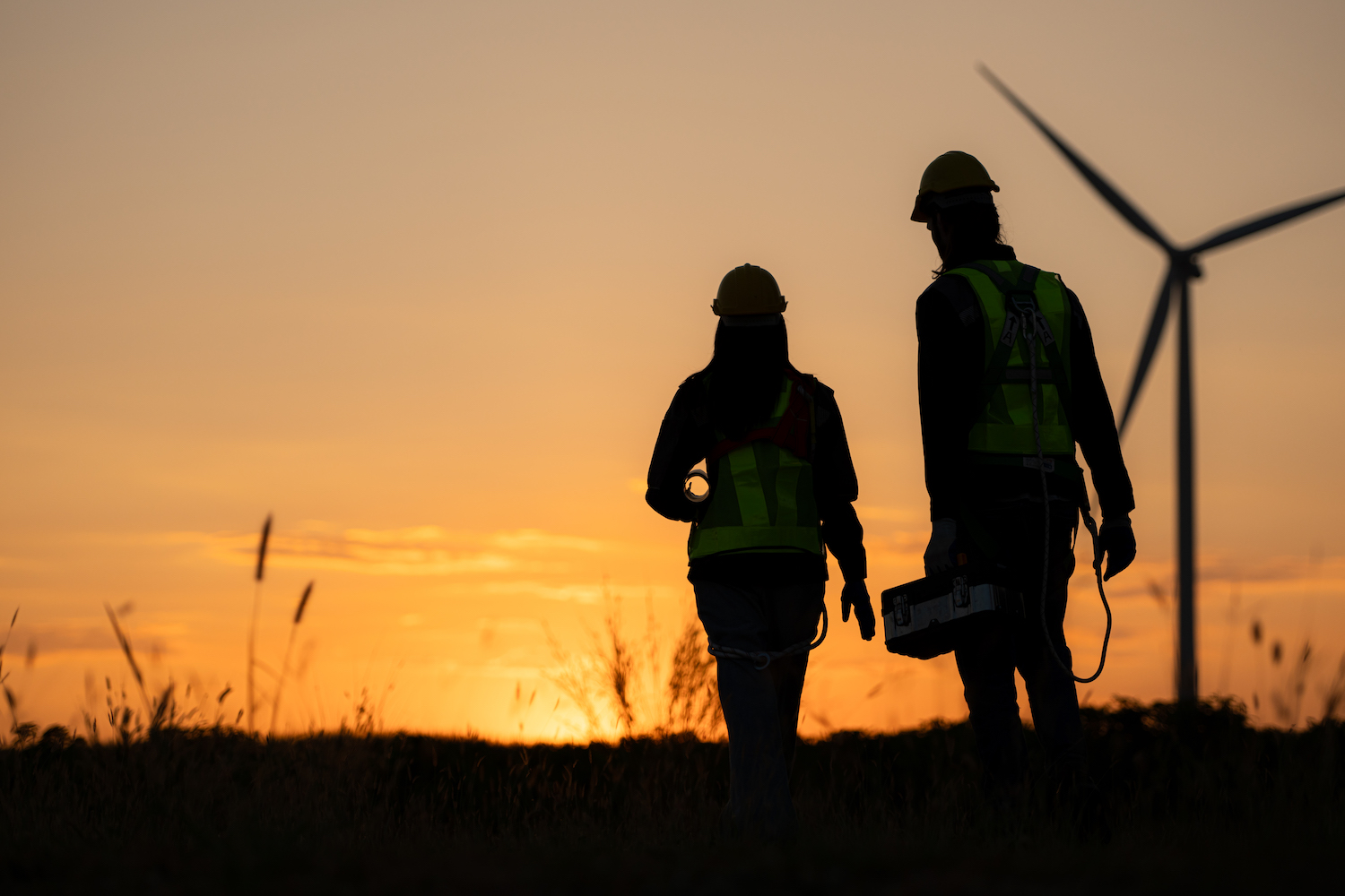 Silhouette of Engineer in charge of wind energy against a background of wind turbines.